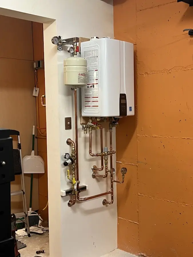 Plumbing technician inspecting water heater connections in Martic